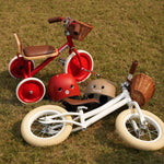 Two children's tricycles and helmets on a grassy field