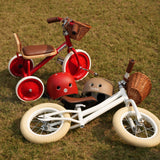 Two children's tricycles and helmets on a grassy field